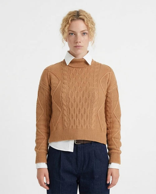 Person wearing a brown cable knit sweater over a white shirt with a plain background