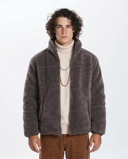 Man wearing a brown fleece jacket over a white sweater on a white background