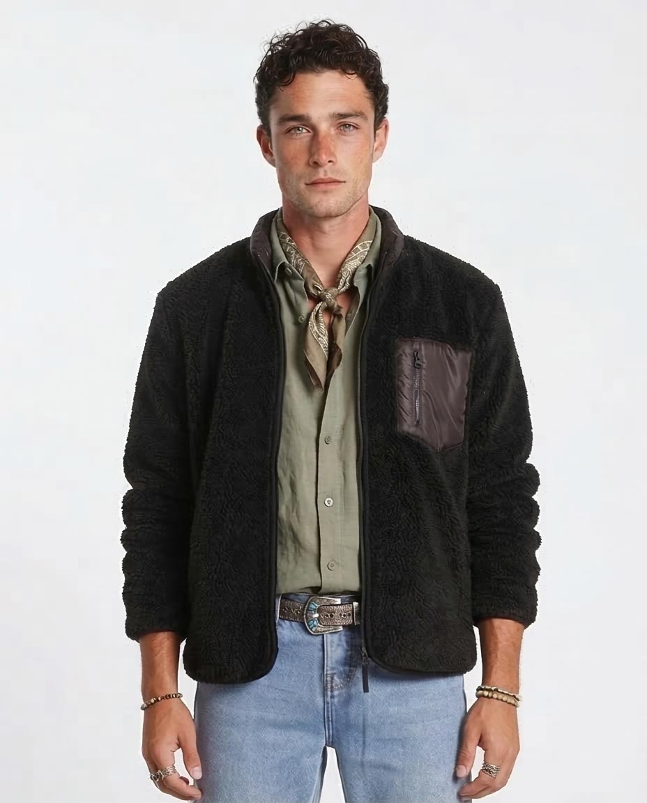 Man wearing a black jacket over a green shirt with blue jeans on a white background