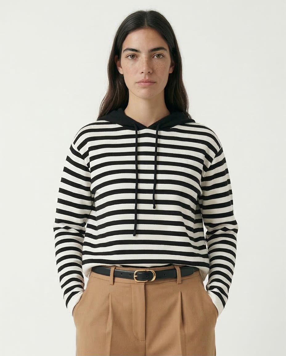 Person wearing a black and white striped hoodie with beige pants on a plain background