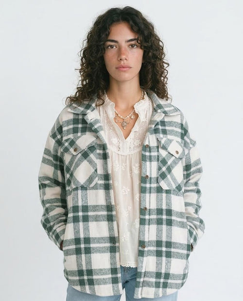 Person wearing a green and white plaid jacket on a plain background
