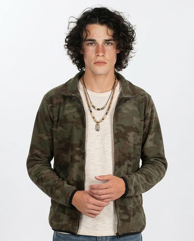 Man wearing a camouflage jacket over a white shirt on a plain background