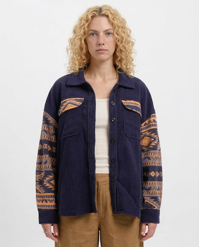 Woman wearing a navy jacket with patterned sleeves on a white background