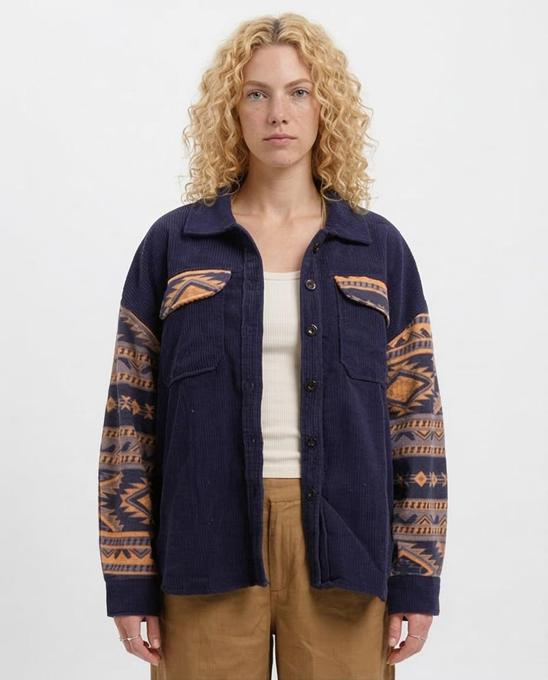 Woman wearing a navy jacket with patterned sleeves on a white background