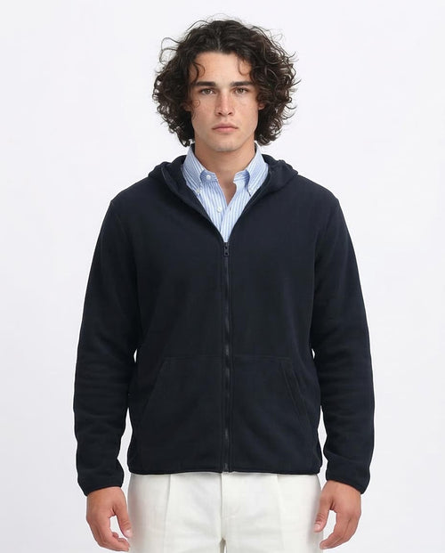 Man wearing a navy blue zip-up hoodie over a light blue shirt on a white background