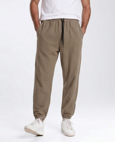 Person wearing beige jogger pants and white sneakers on a white background