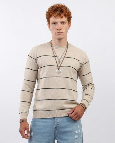 Man wearing a beige striped sweater and light blue jeans against a white background