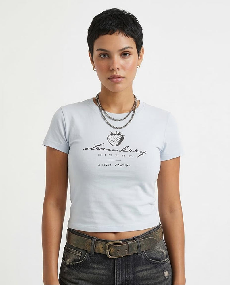 Person wearing a white t-shirt with 'Strawberry Bistro' logo on a plain background