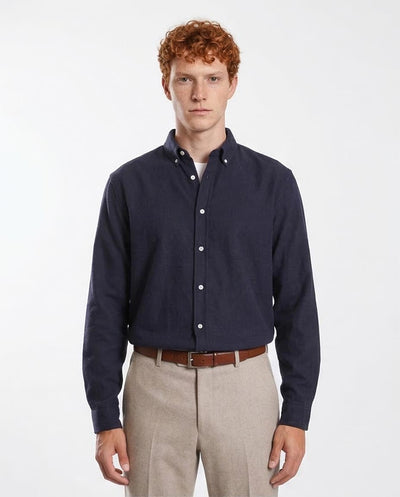 Man wearing a navy button-up shirt and beige pants on a white background