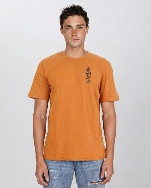 Man wearing an orange t-shirt with a logo on a plain background