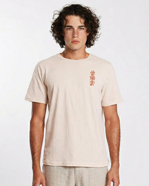 Man wearing a beige t-shirt with red text on a white background