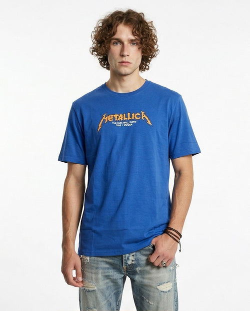 Man wearing a blue 'Metallica' t-shirt on a white background