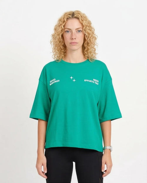 Person wearing a green t-shirt with text on a plain background