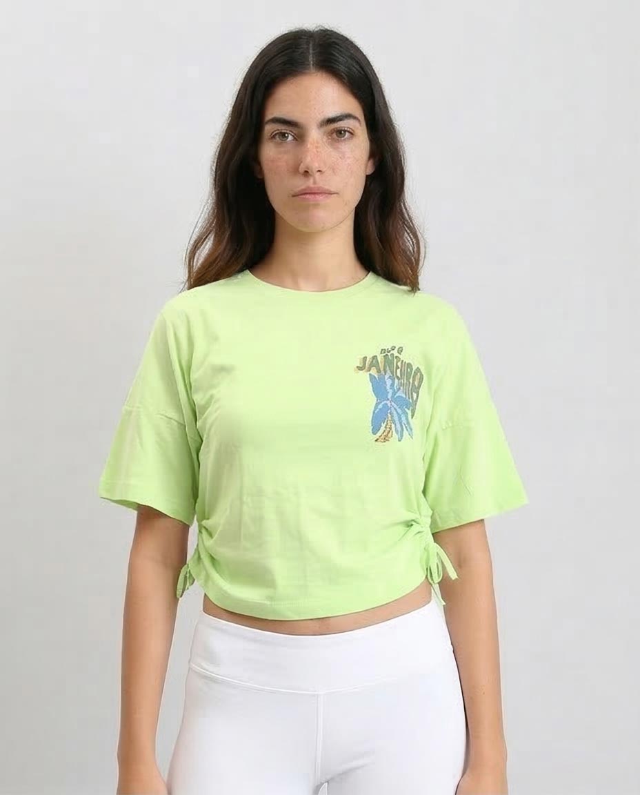 Woman wearing a light green t-shirt with a graphic design on a plain background