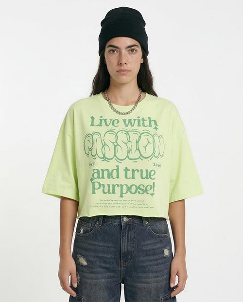 Person wearing a light green t-shirt with text and dark jeans on a white background