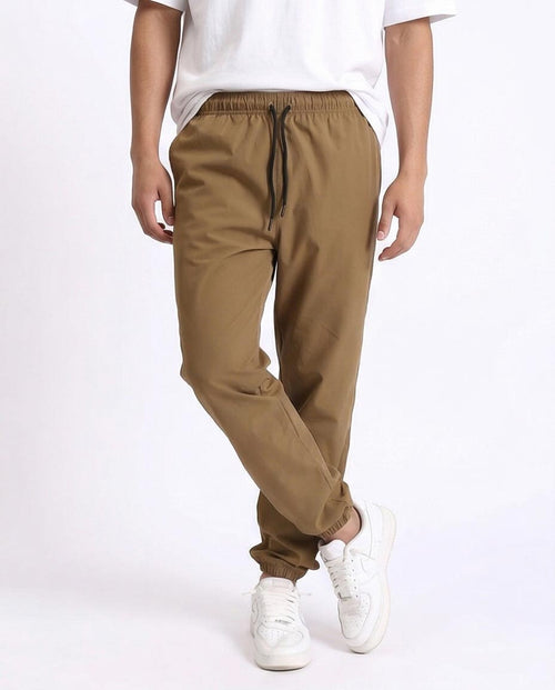 Person wearing brown pants and white sneakers on a white background