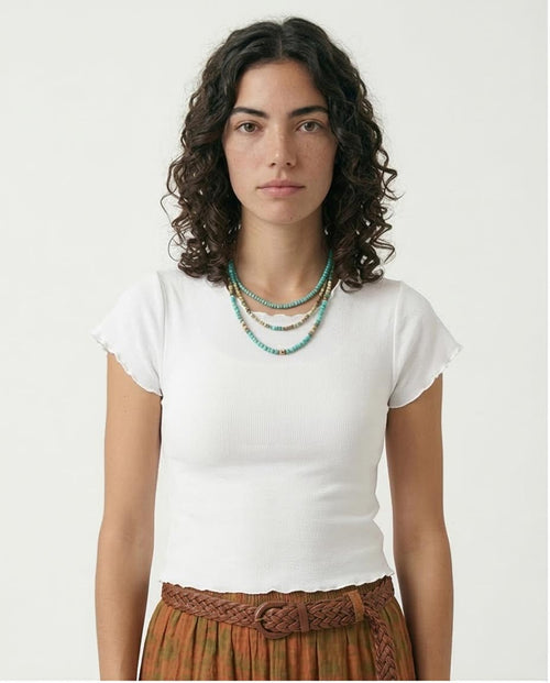 Woman wearing a white t-shirt and brown skirt with a plain background