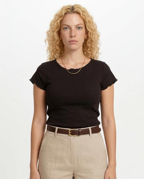 Woman wearing a black t-shirt and beige pants on a white background