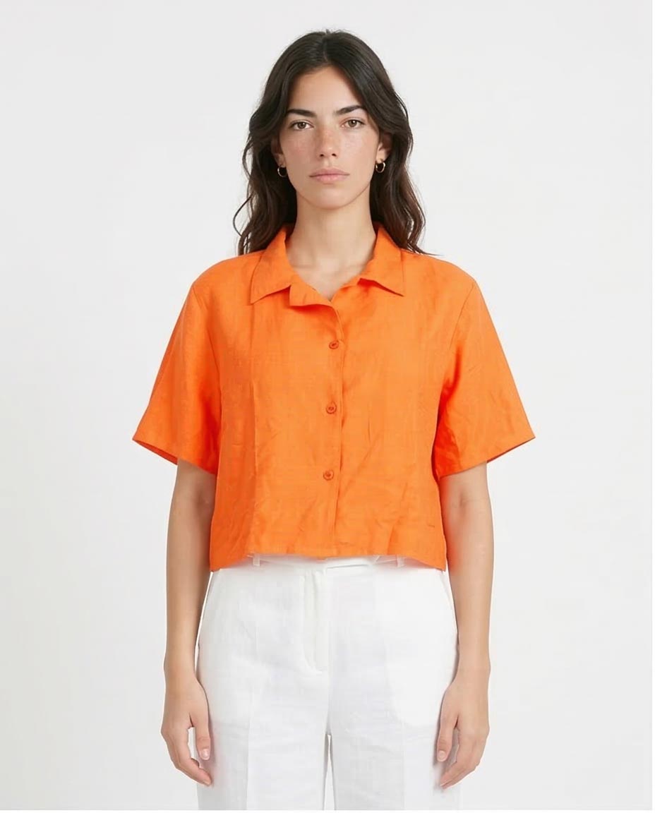 Woman wearing an orange shirt and white pants on a plain background