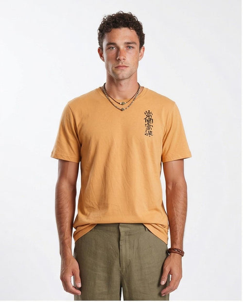 Man wearing a mustard yellow t-shirt with black text on a white background