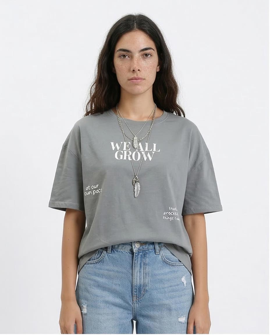 Person wearing a gray t-shirt with text and blue jeans on a white background