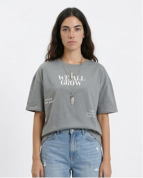 Person wearing a gray t-shirt with text and blue jeans on a white background