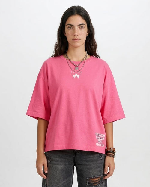 Person wearing a pink oversized t-shirt with text on a plain background