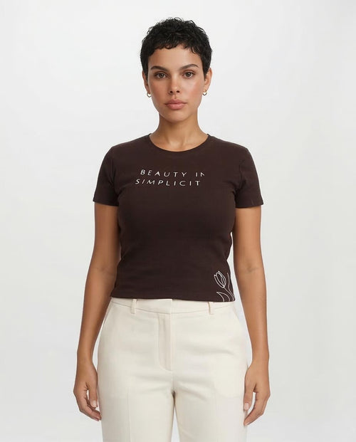 Woman wearing a brown t-shirt with 'BEAUTY IS SIMPLICITY' text on a white background
