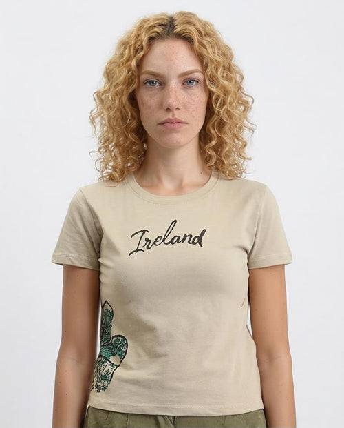 Woman wearing a beige t-shirt with 'Ireland' printed on it against a white background