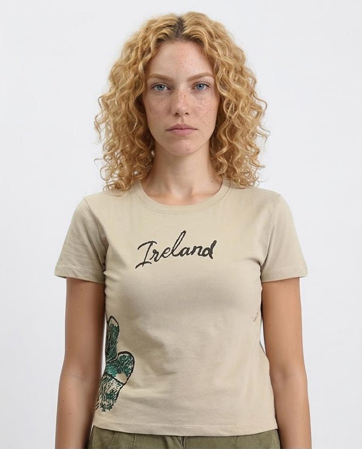 Woman wearing a beige t-shirt with 'Ireland' printed on it against a white background