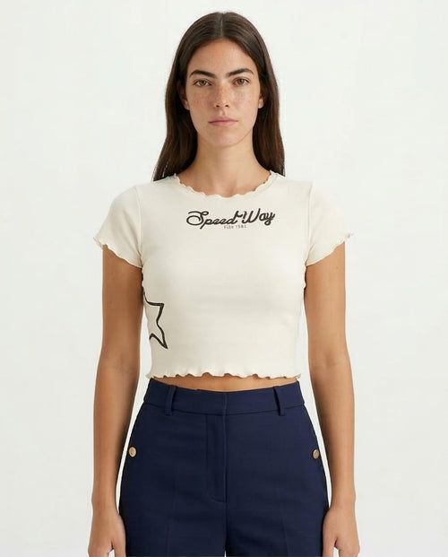 Woman wearing a white t-shirt with 'Speed Way' text and navy pants on a white background