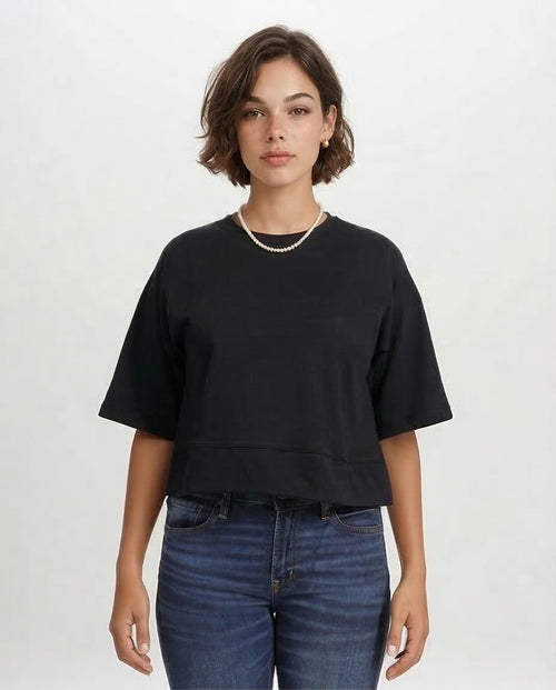 Person wearing a black oversized t-shirt and blue jeans on a white background
