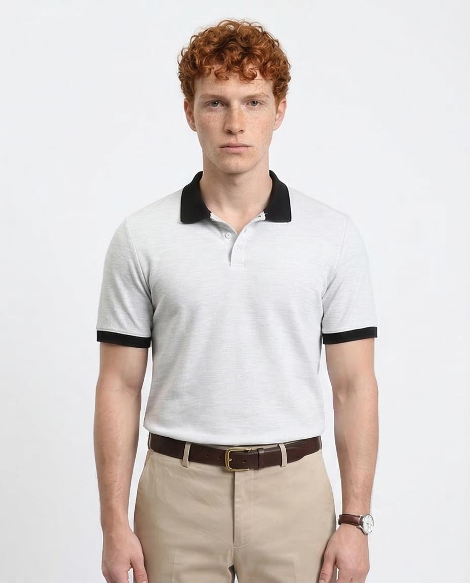 Man wearing a white polo shirt with black trim on a plain background