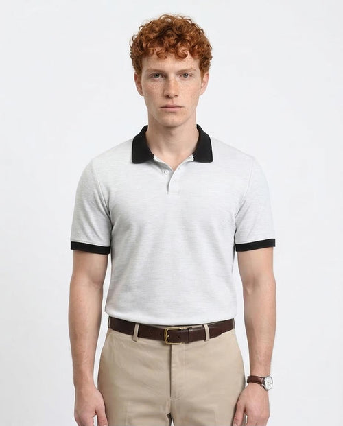 Man wearing a white polo shirt with black trim on a plain background