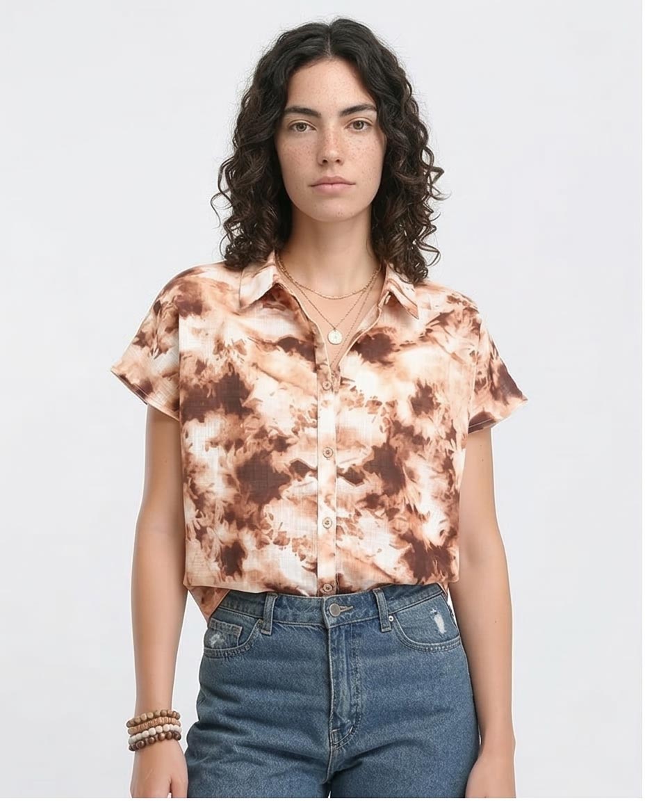 Woman wearing a tie-dye shirt and jeans on a plain background