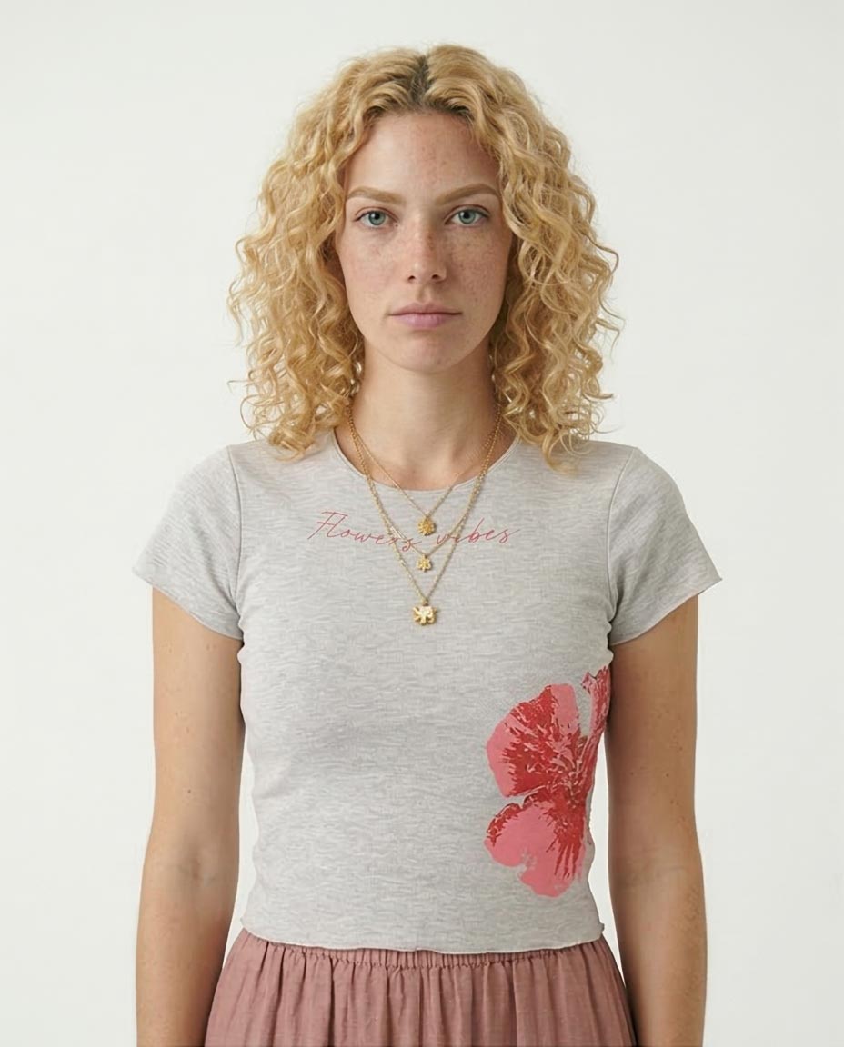 Woman wearing a gray t-shirt with a pink flower design on a plain background