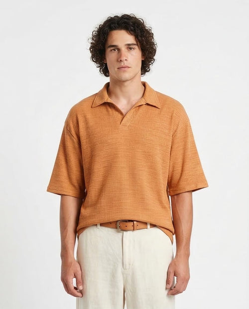 Man wearing a brown textured shirt and white pants on a light gray background