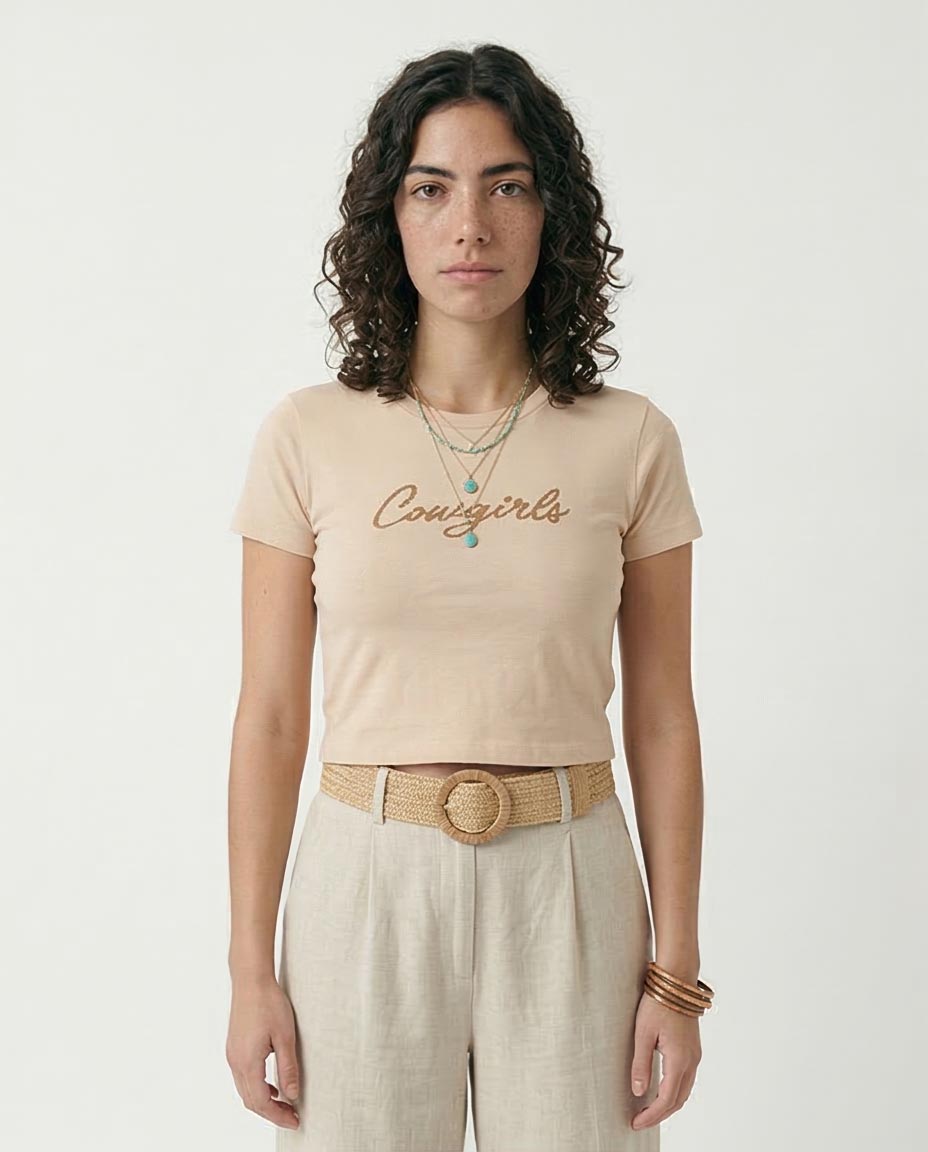 Woman wearing a beige t-shirt with 'Conscious' text, standing against a plain background