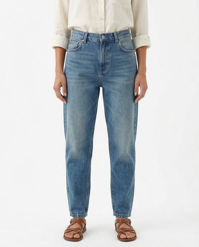 Woman wearing blue jeans and a beige shirt on a white background