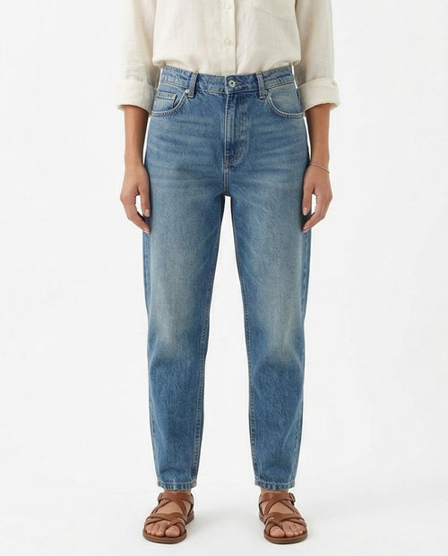 Woman wearing blue jeans and a beige shirt on a white background