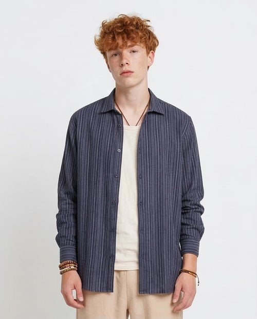 Man wearing a blue striped shirt over a beige shirt on a white background