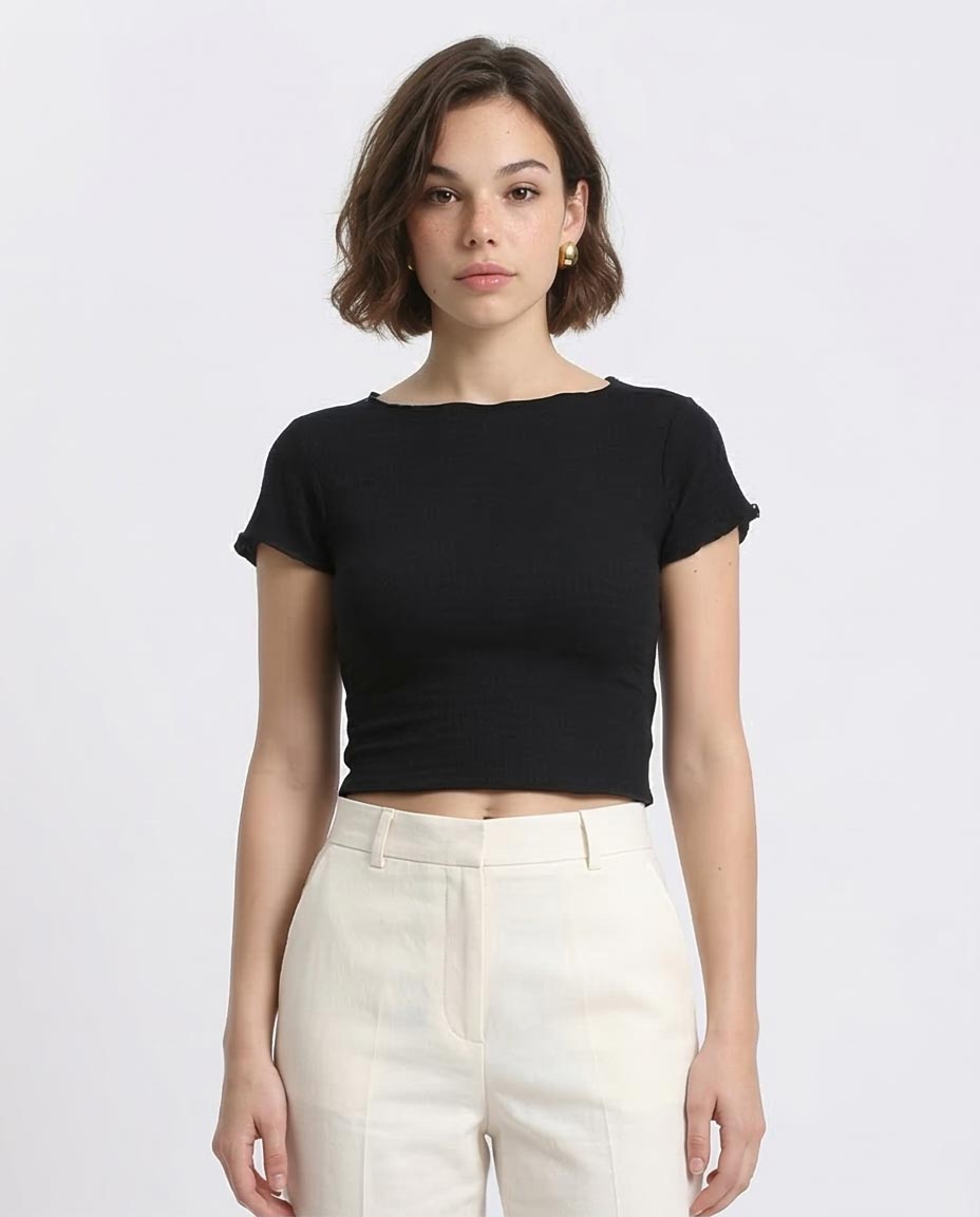 Person wearing a black crop top and white pants on a plain background
