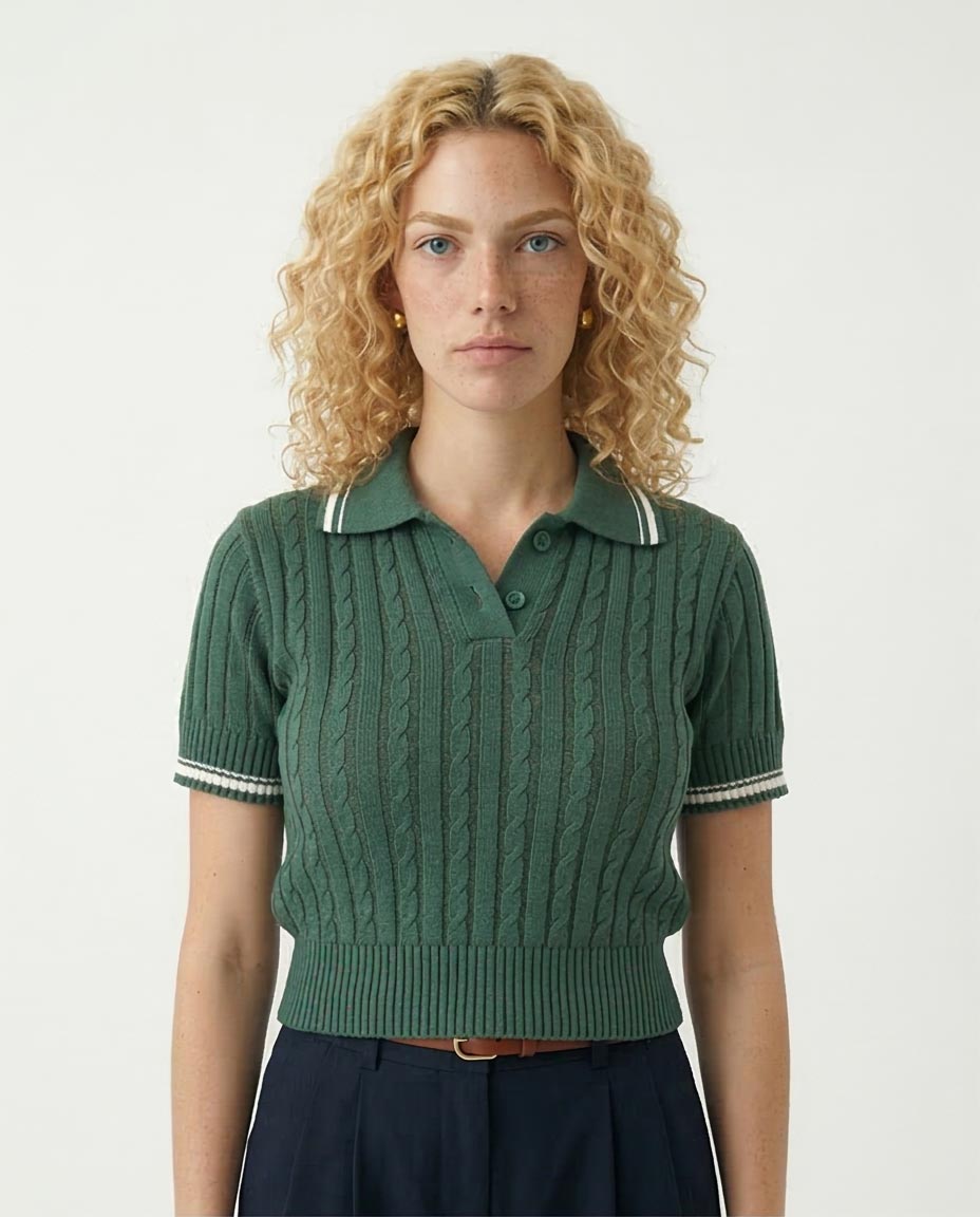 Woman wearing a green knitted polo shirt with white trim on a plain background