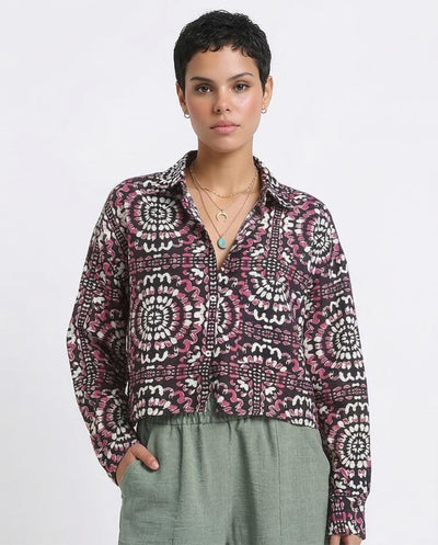 Woman wearing a patterned shirt and green pants on a white background