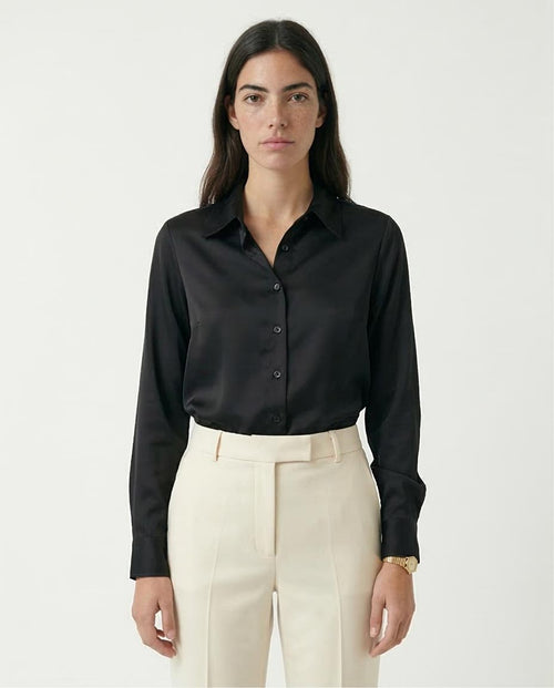 Woman wearing a black shirt and beige pants on a white background