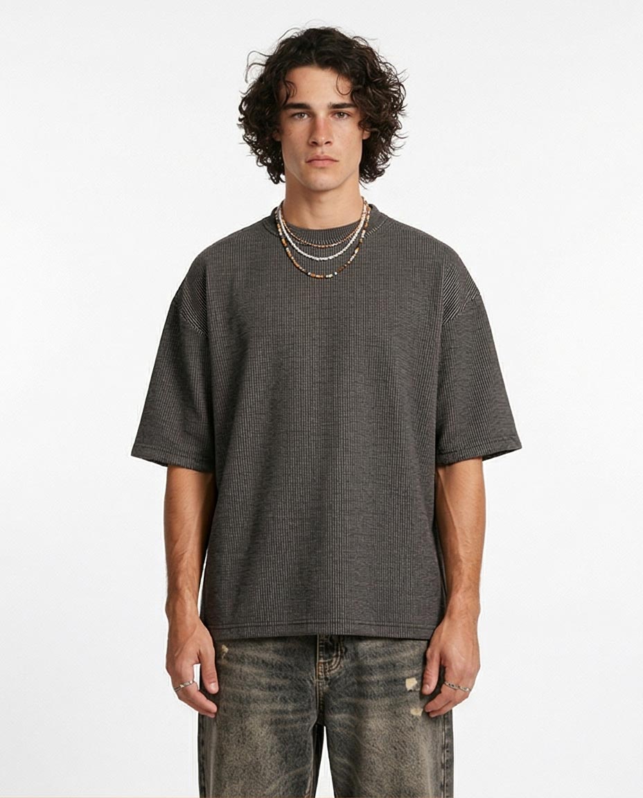 Man wearing a gray oversized t-shirt and jeans on a white background