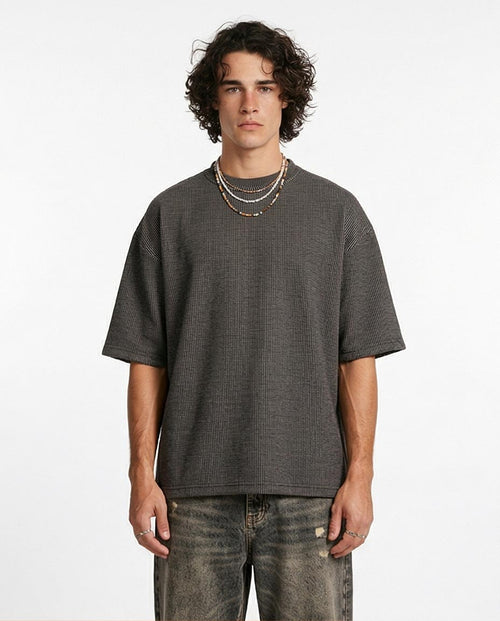 Man wearing a gray oversized t-shirt and jeans on a white background