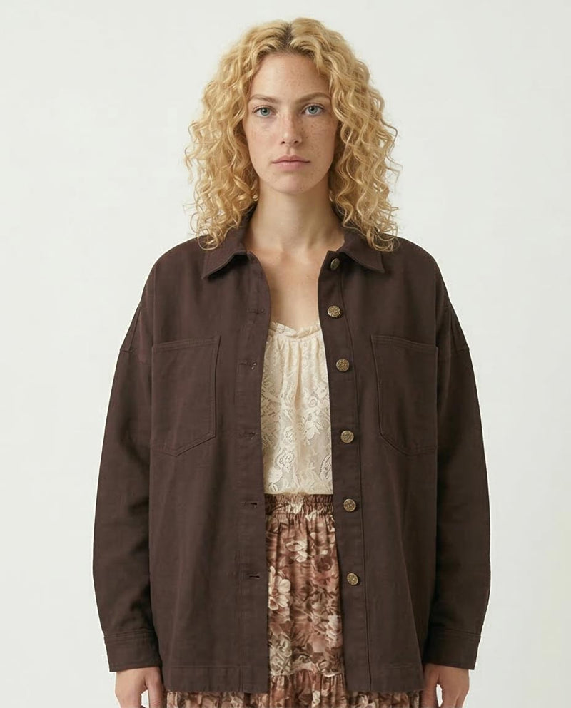 Woman wearing a Black Shirt jacket over a patterned dress on a white background