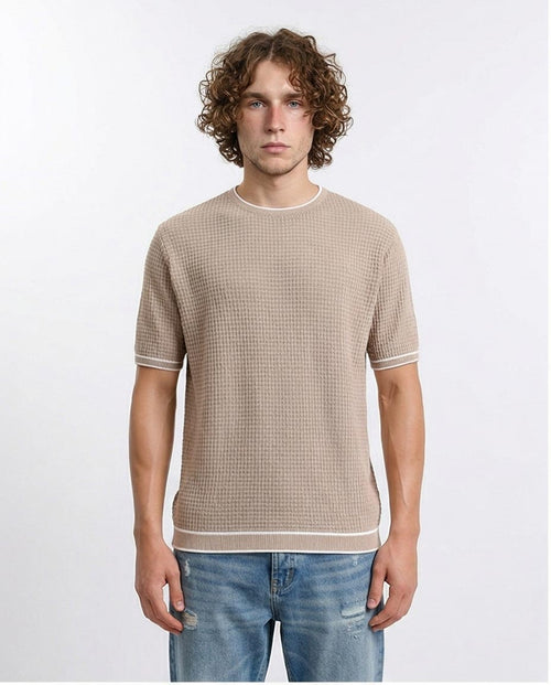 Man wearing a beige checkered shirt and blue jeans on a white background