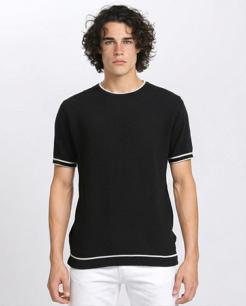 Man wearing a black short-sleeve shirt with white trim on a white background